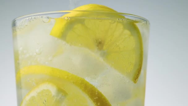 Vidro rotativo de água espumante gelada e fatias de limão — Vídeo de Stock