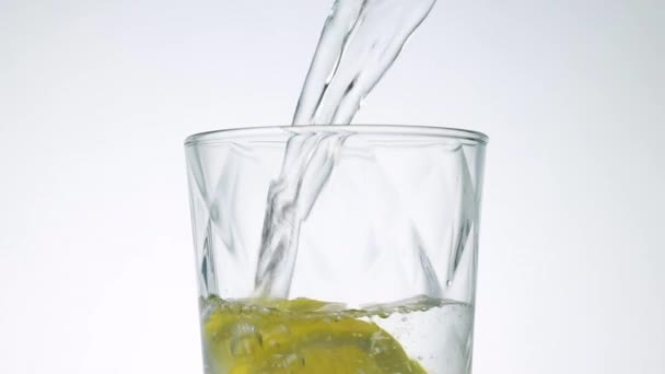 Detailní záběr studené čerstvé nehybné vody nalévající se do sklenice s citronovými plátky, zpomalený pohyb — Stock video