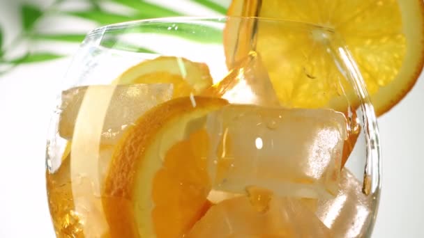 Refrigerante espumante limonada macia derramando em vidro com cubos de gelo e fatias de laranja closeup — Vídeo de Stock
