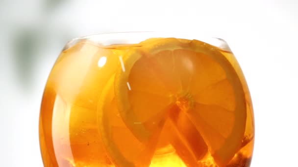 Nahaufnahme eines Aperol Spritz Cocktails mit Orangenscheiben und Eiswürfeln auf weißem Hintergrund — Stockvideo