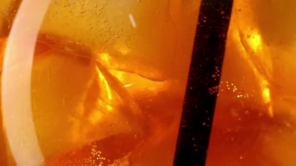 Zblízka oranžový koktejl s kostkami ledu pití s černou slámou zpomalení — Stock video