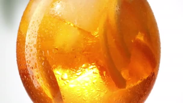 젖은 오렌지 아이스 칵테일 잔이 하얀 배경 위를 덮고 있다 — 비디오