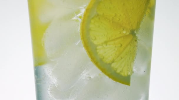 Vidro rotativo de água espumante gelada e fatias de limão close-up — Vídeo de Stock