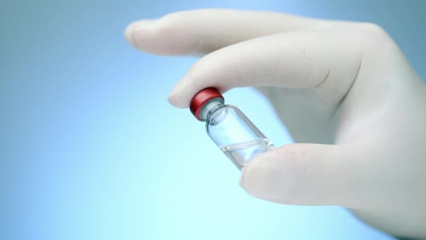 Doktorların elindeki tıbbi aşı şişesini kapat. Mavi arka plan. — Stok video