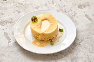 Beyaz tabakta erimiş tereyağlı patates püresi.