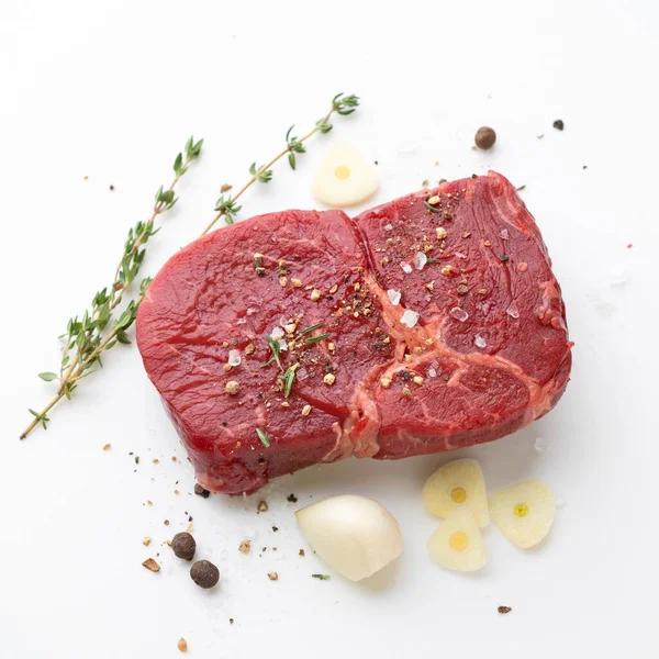 新鮮な生牛のステーキ肉とスパイスの白を背景にトップビュー — ストック写真
