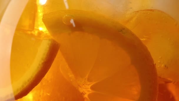 Zpomalený pohyb zblízka otáčení oranžové aperol spritz koktejlové sklo s kostkami ledu a plátky ovoce — Stock video