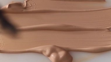 beige smear of tonal foundation cream background close up, smudge with a brush, beautiful pastel texture, cosmetic product for make up