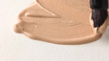 beige smear of tonal foundation cream close up, smudge with a brush, beautiful pastel texture, cosmetic product for make up