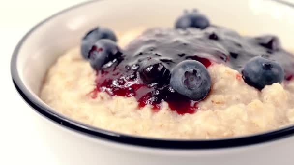 Rotating Bowl Freshly Made Oatmeal Porridge Blackcurrant Jam Fresh Blueberries — Stock Video