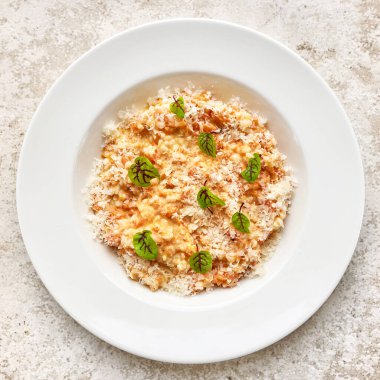 portion of risotto with parmesan on white restaurant plate, top view