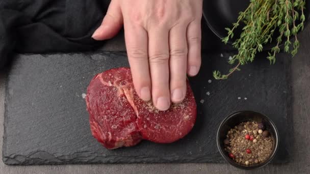 Cozinheiro adicione tomilho à carne crua fresca de bife para grelhar, vista superior preparação de close-up — Vídeo de Stock