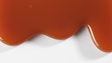 Beyaz arkaplanda erimiş karamel sosu makrosu akışını kapat