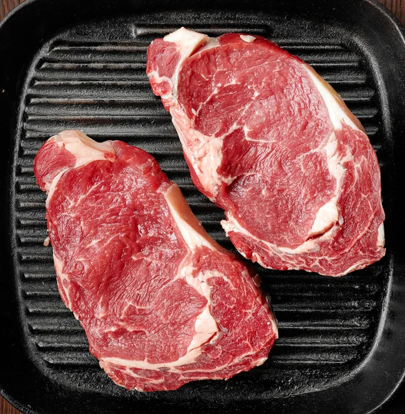 Raw beef steak on cooking pan — Stock Photo, Image