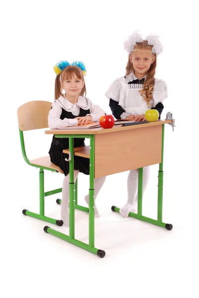 Pequenas alunas sentadas em uma mesa — Fotografia de Stock