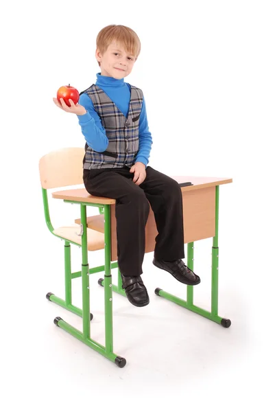 Boy sitting on the school desk and holding apple — Stock Photo, Image