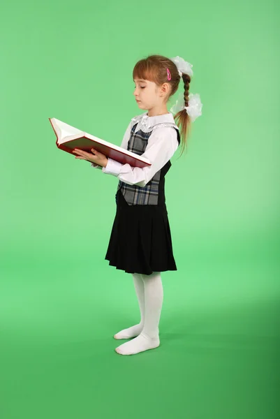 Menina em uniforme escolar lendo um livro — Fotografia de Stock