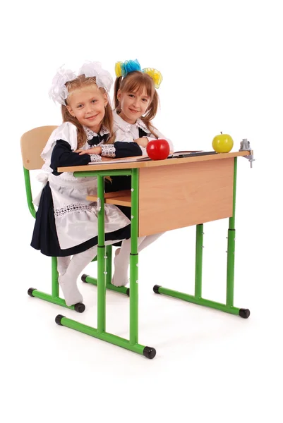 Little schoolgirls sitting at a desk — Stock Photo, Image