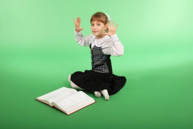 Kız Açık bir kitap önünde oturan bir okul üniformalı