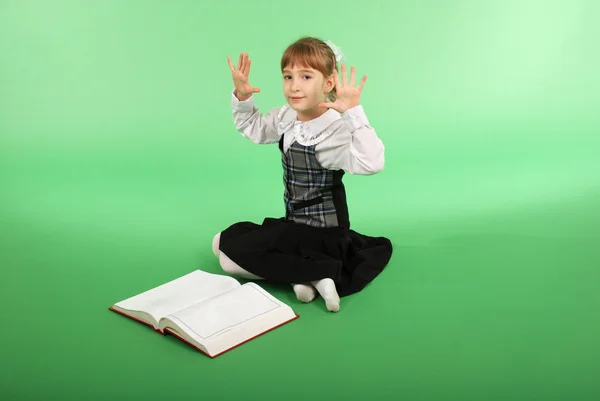 Fille en uniforme scolaire assis devant un livre ouvert — Photo