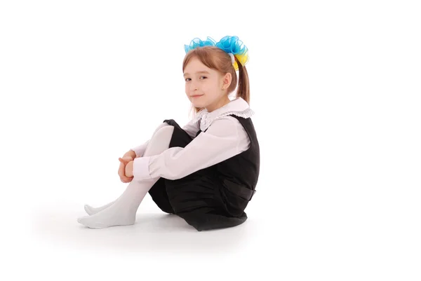 Meisje in schooluniform zitten en glimlachen — Stockfoto