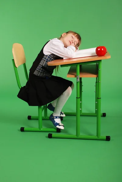 Menina em uniforme escolar dormindo em sua mesa — Fotografia de Stock