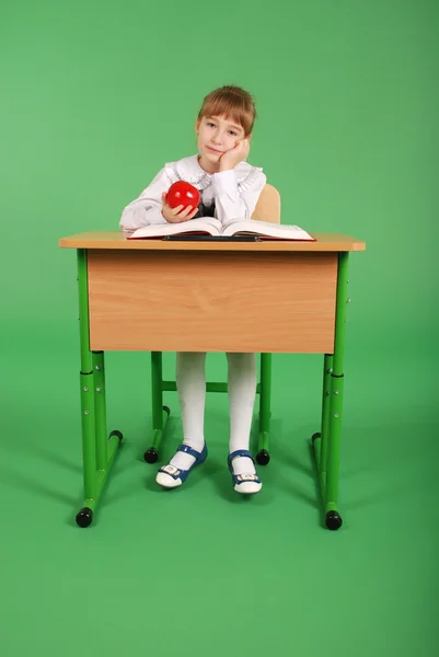 Girl in a school uniform sitting at a desk — Stock Photo, Image