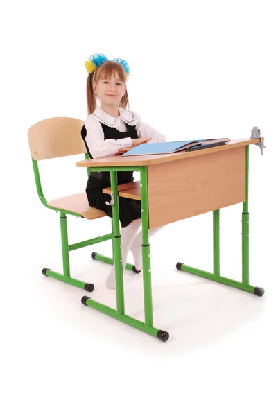 Jenta i skoleuniform sitter ved et skrivebord – stockfoto