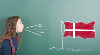 Tahtaya Danimarka bayrağını asan ergenlik öncesi kız. Yüksek çözünürlüklü. Tam alan derinliği. 