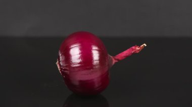 Kırmızı soğan yerçekimi tarafından hareket ettirilir. Siyah bir ayna yüzeyinde.