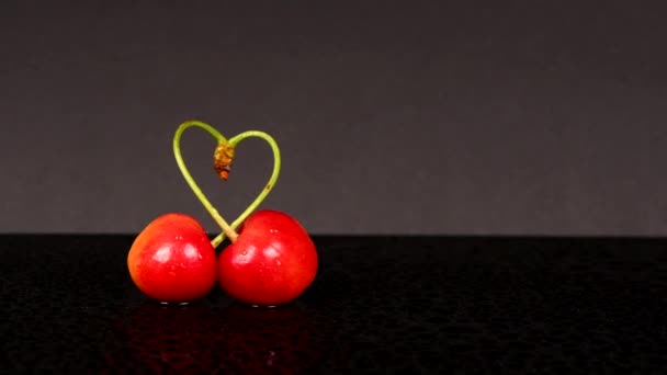 心臓の愛に結び付けられた滴を持つ2つのチェリー 白い背景に甘い桜の愛のサイン 絡み合った茎を持つ2つのハート型の果実 Uhdビデオ映像3840X2160 — ストック動画