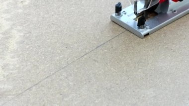 Bir marangoz elektrikli testereyle kontrplak kumaşı testereyle keser. Testereyle yakın plan çekimde çalışıyorum. Elektrikli yapboz ve kontrplakla çalışan marangoz ustası. 4K UHD video görüntüsü 3840X2160