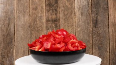 Ahşap arka planda bir tabak tatlı biber. Döngü hareketi. Yan görüş. Rotasyon 360. 4K UHD video görüntüsü 3840X2160.