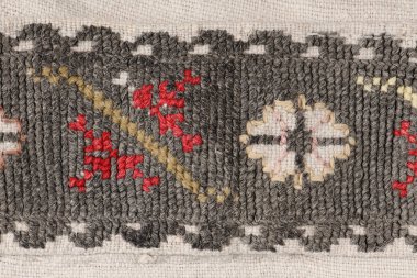 Kırmızı ve beyaz geometrik nakışlarla süslenmiş koyu gri dokuma kumaşın makro ayrıntıları. Kırsal kış tekstil arka planı.