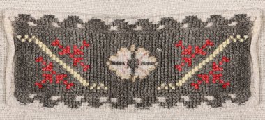 Kırmızı ve beyaz geometrik nakışlarla süslenmiş koyu gri dokuma kumaşın makro ayrıntıları. Kırsal kış tekstil arka planı.