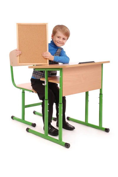 Chlapec sedí ve školní lavici a drží desky — Stock fotografie