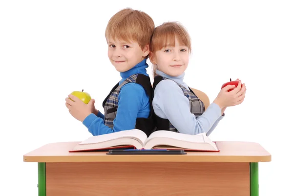 Garçon et fille assis à un bureau de l'école et tenant pomme — Photo