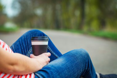 Kahve Kupası ile kız oturuyor