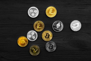 Ahşap zemin üzerinde bitcoin, dalgalanma ve ethereum sembollü gümüş ve altın sikkeler.