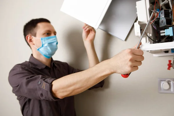 a man repairing a boiler in a medical mask