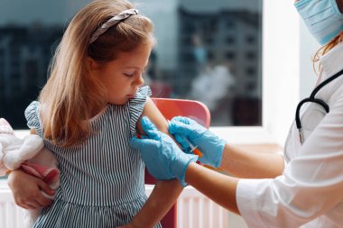Çocuk aşısı. Hastanede bir çocuğu muayene eden bir doktor. covid-19