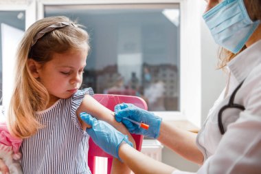 Çocuk aşısı. Hastanede bir çocuğu muayene eden bir doktor. covid-19