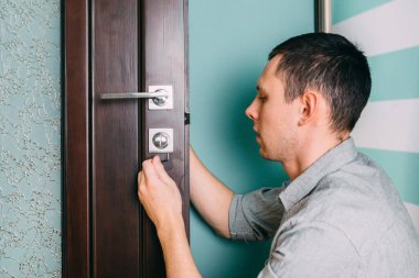 Adam kapı kolunu tamir ediyor. Marangoz kapı tokmakları ile kilit kurulumu üzerinde çalışıyor ahşap kapı