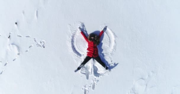 Menina encontra-se na neve e faz um anjo. — Vídeo de Stock