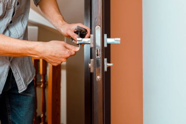 Adam kapı kolunu tamir ediyor. Yeni kapı dolabı döşenirken işçi ellerine yakın çekim