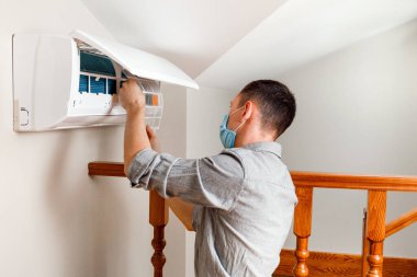 Erkek teknisyen içeride klimayı temizliyor.