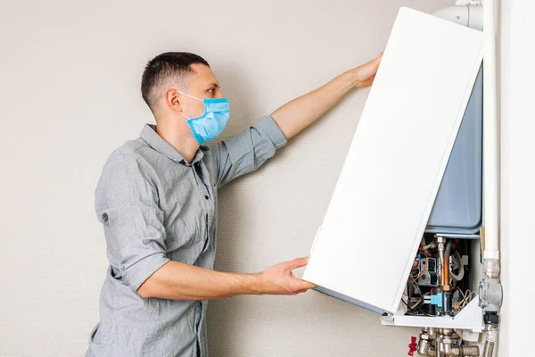 Plumber attaches Trying To Fix the Problem with the Residential Heating Equipment. Repair of a gas boiler