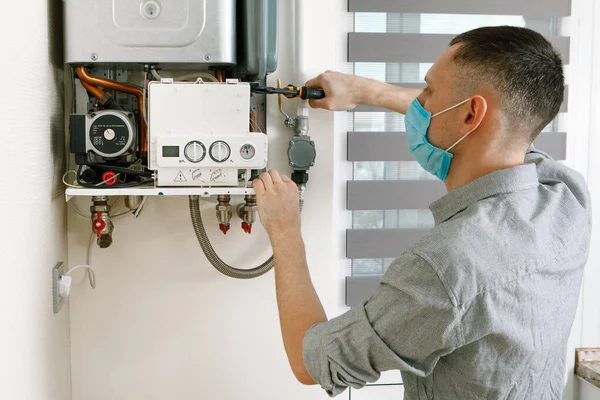 Plumber attaches Trying To Fix the Problem with the Residential Heating Equipment. Repair of a gas boiler