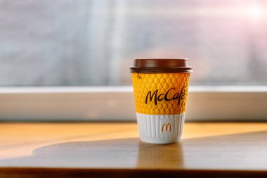 McDonalds restoranında McCafe kahvesi. Masada sarı kahve fincanı ve güneşten gelen gölgeler. Kahvaltı zamanı, kahve zamanı. UKRAINE, ROVNO 26 Mart