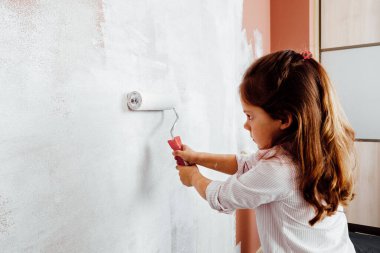 Baba ve kızı odadaki duvarı boyuyor. konut yenileme